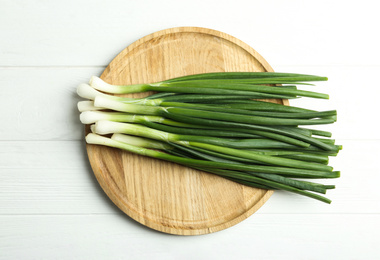 Fresh green spring onions on white wooden table, top view