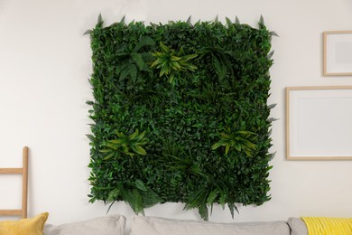 Green artificial plant panel on light wall in room