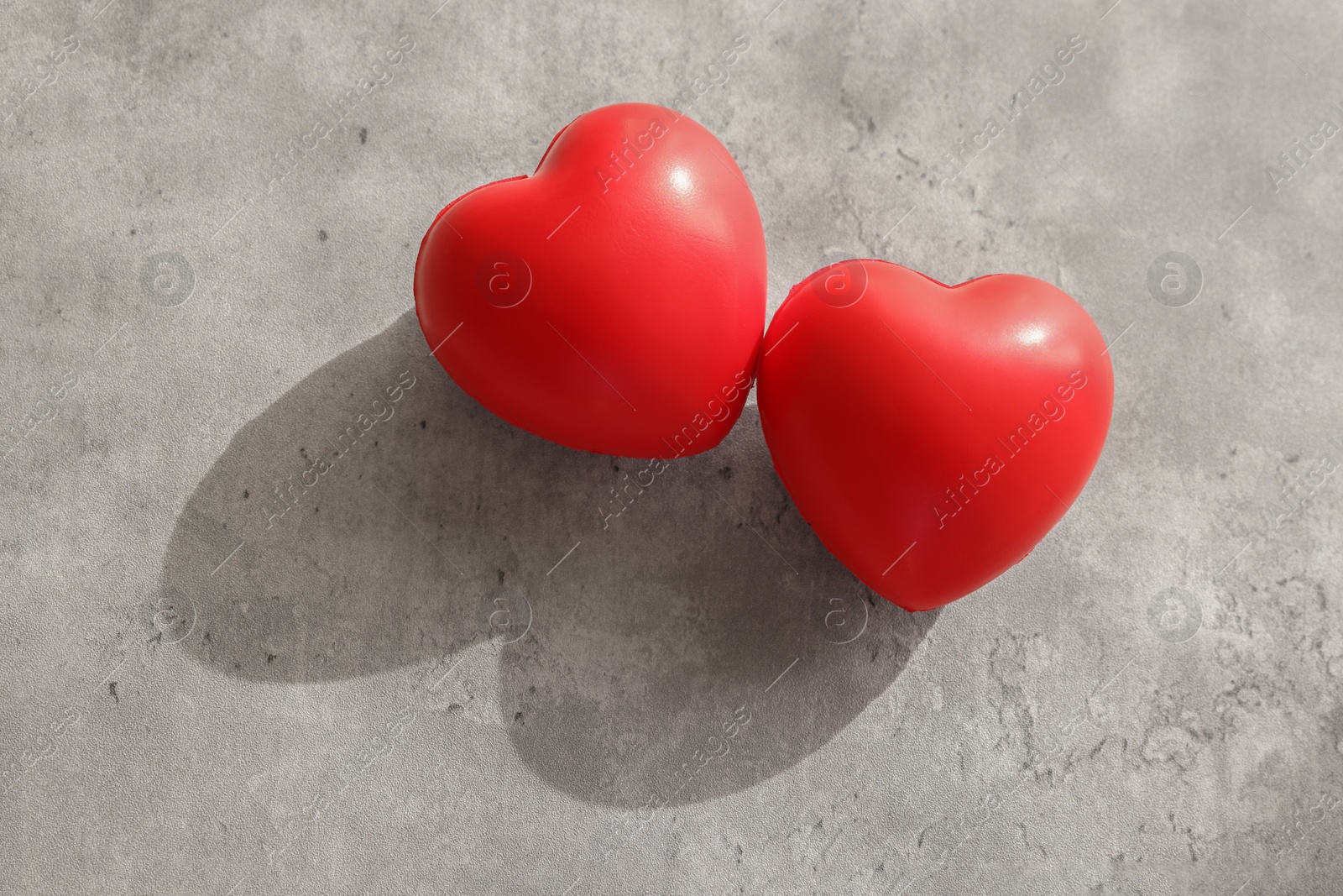 Photo of Two decorative hearts on gray textured table, above view