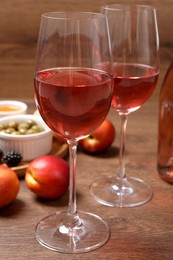 Delicious rose wine and snacks on wooden table