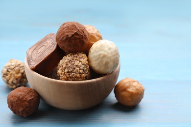 Tasty chocolate candies on light blue wooden table