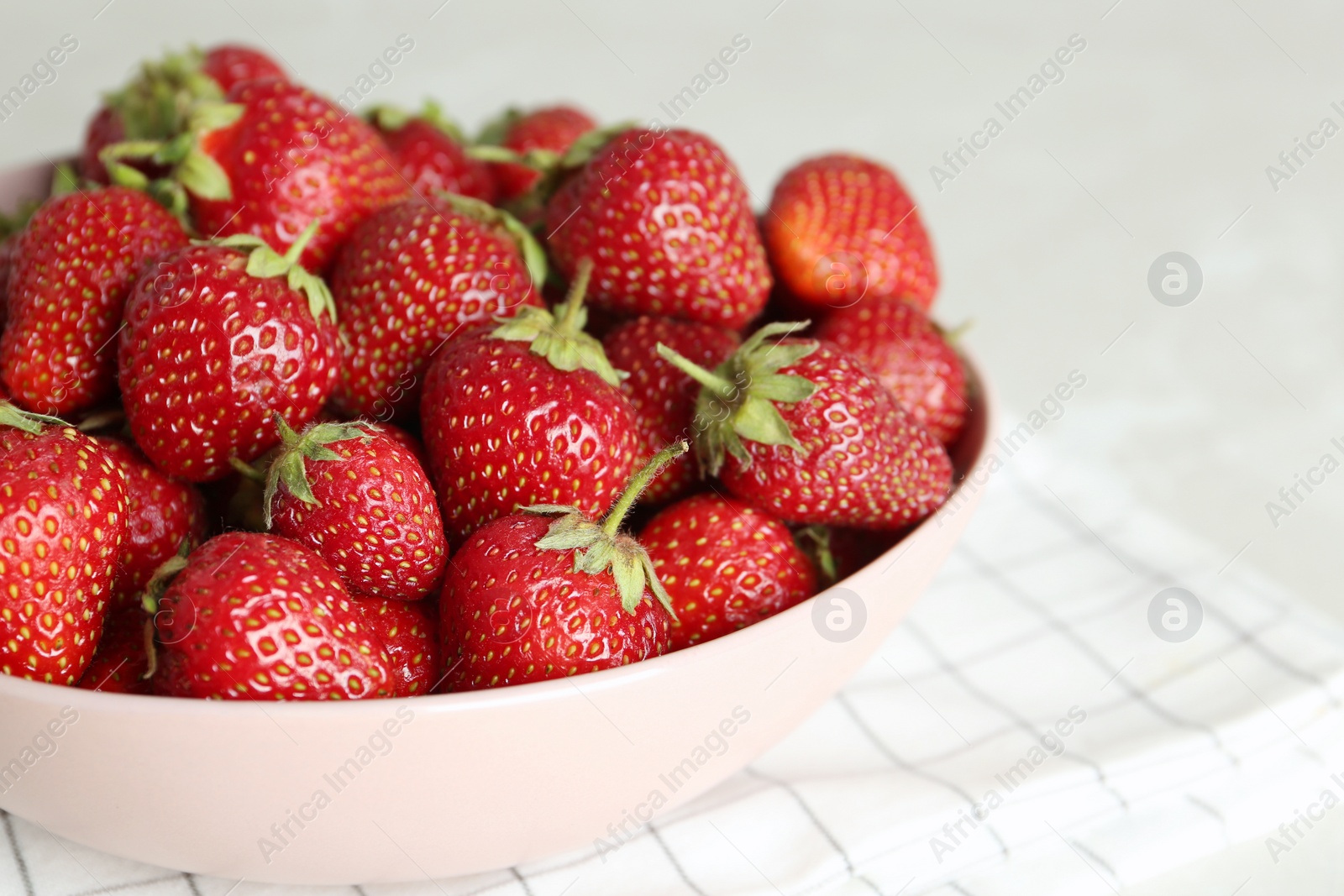 Photo of Delicious ripe strawberries in bowl on table, closeup