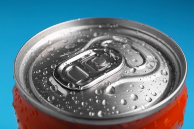 Photo of Energy drink in wet can on light blue background, closeup