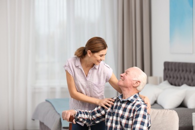 Photo of Elderly man with female caregiver at home. Space for text