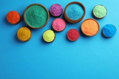Photo of Colorful powders in bowls on light blue background, flat lay with space for text. Holi festival celebration