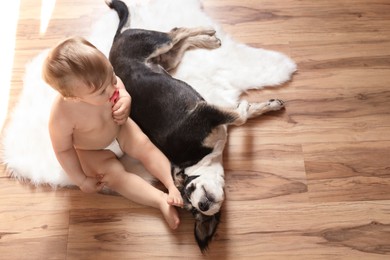 Adorable baby with pacifier and cute dog on faux fur rug, above view