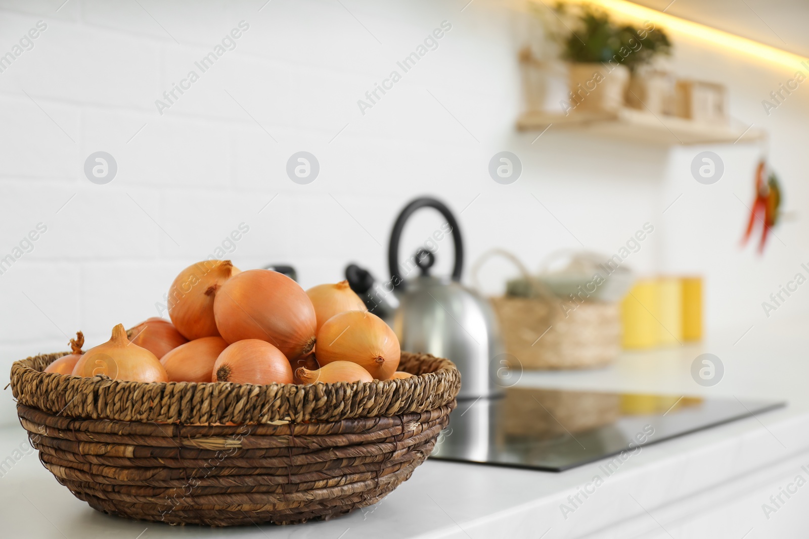 Photo of Fresh onions on white countertop in modern kitchen. Space for text