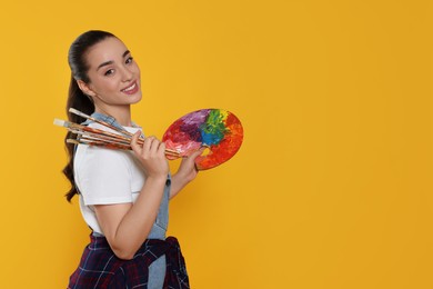 Photo of Woman with painting tools on yellow background, space for text. Young artist