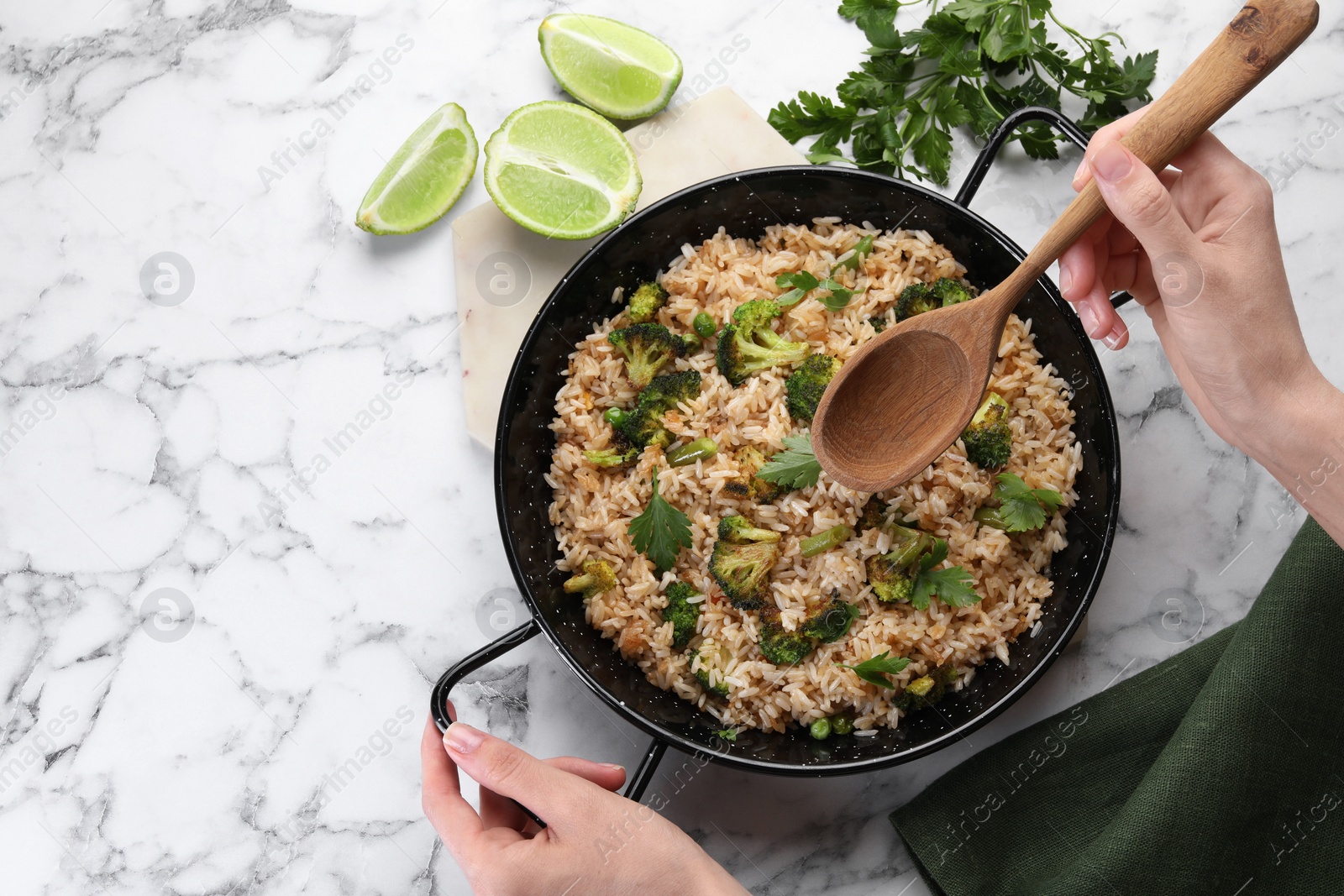 Photo of Woman with tasty fried rice and wooden spoon at white marble table, top view. Space for text