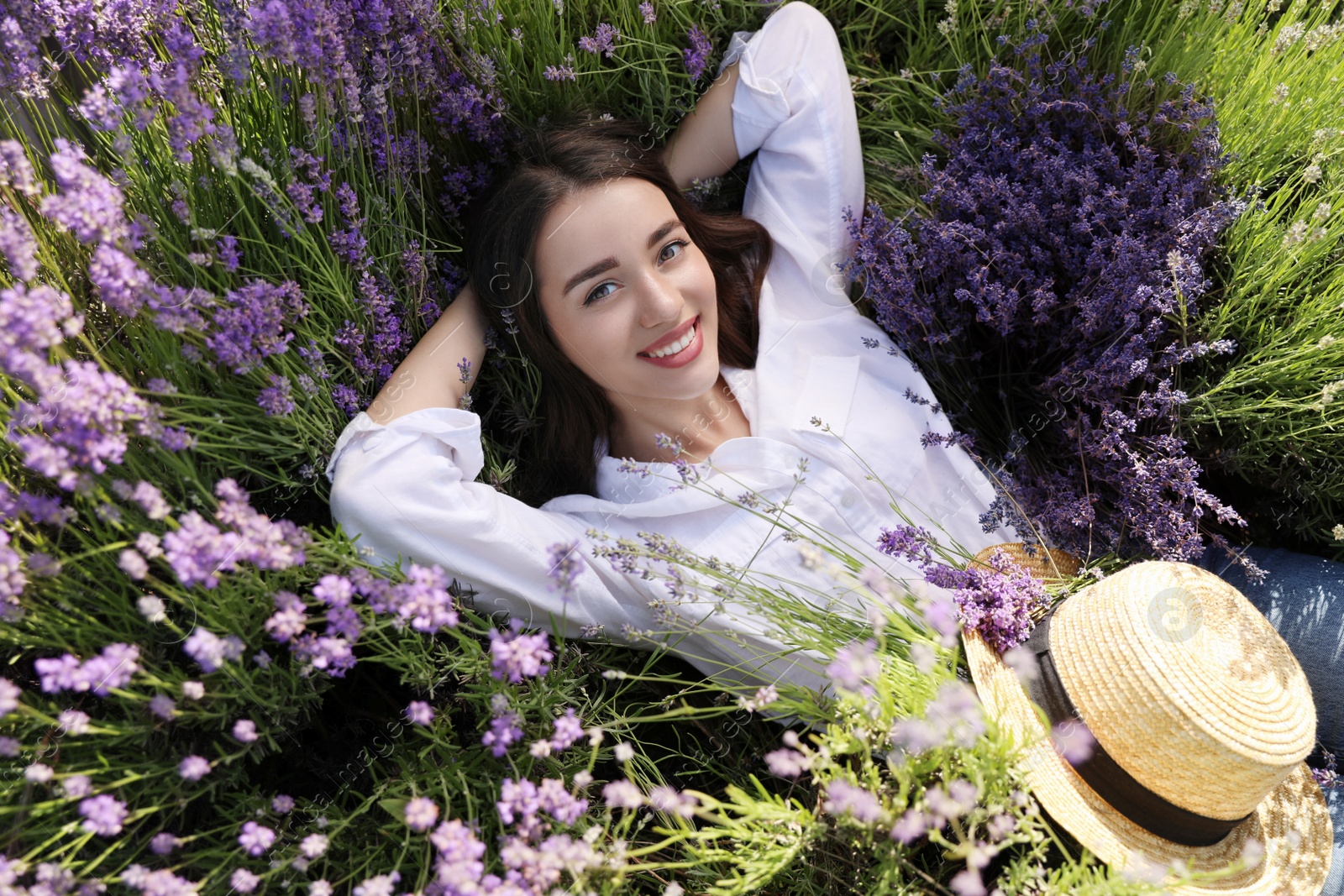 Photo of Young woman lying in lavender field on summer day