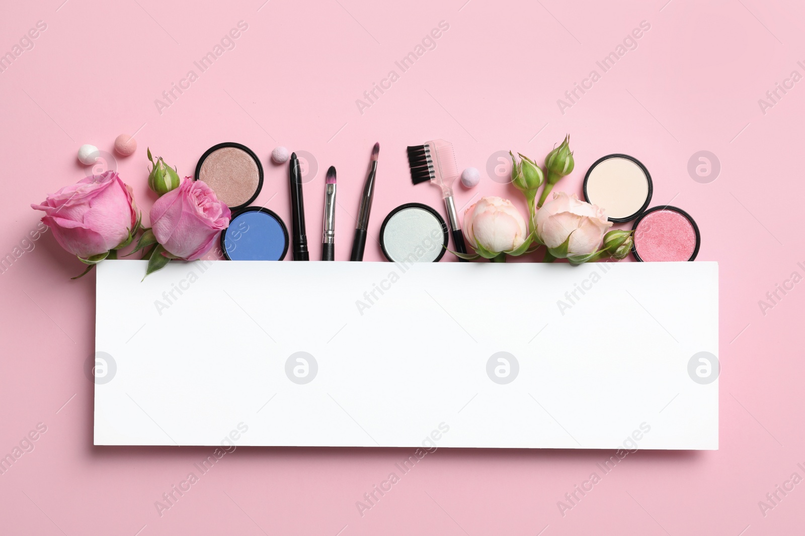 Photo of Flat lay composition with card and products for decorative makeup on pastel pink background