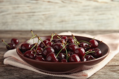 Plate with sweet red cherries on wooden table