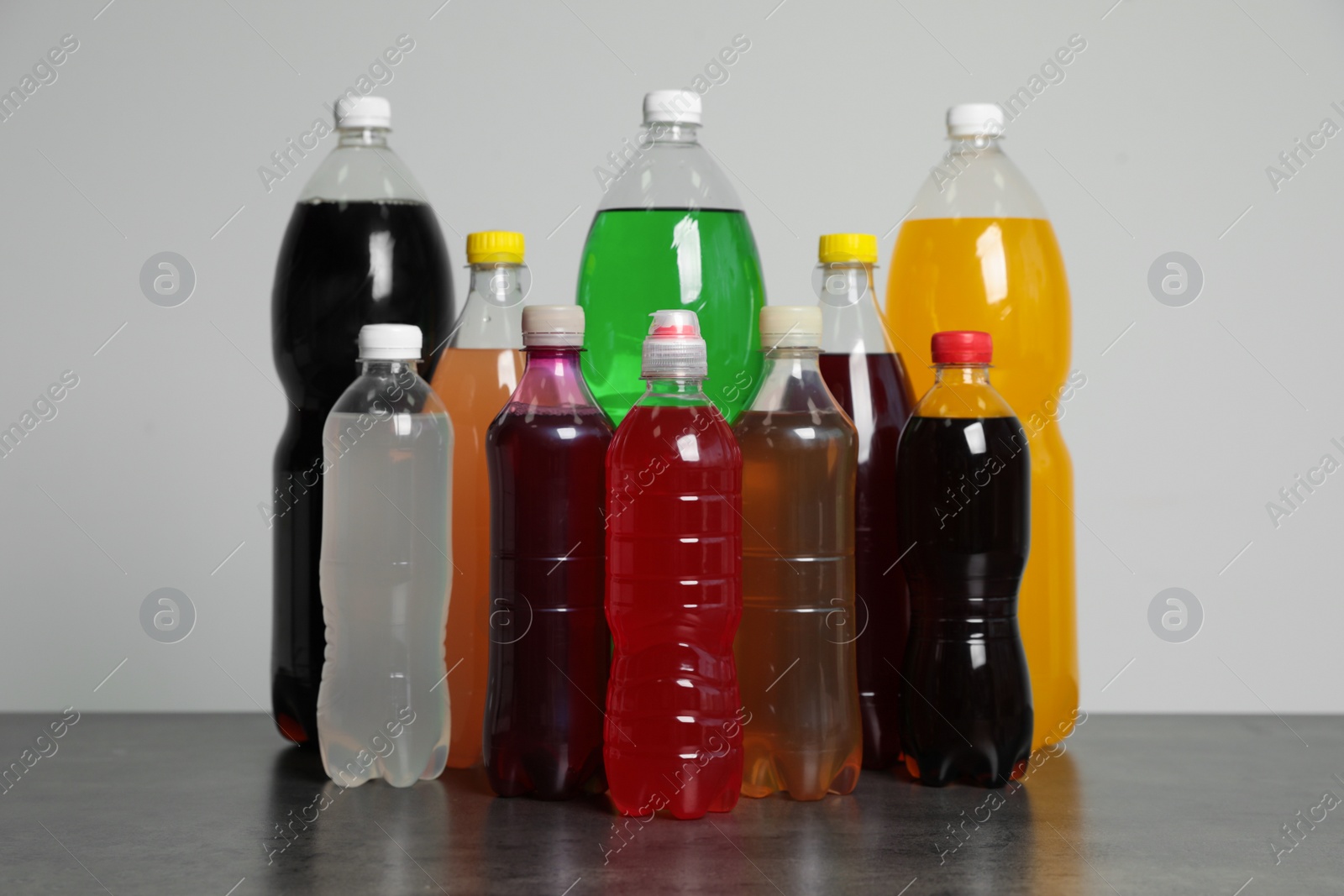 Photo of Bottles of soft drinks on table against grey background