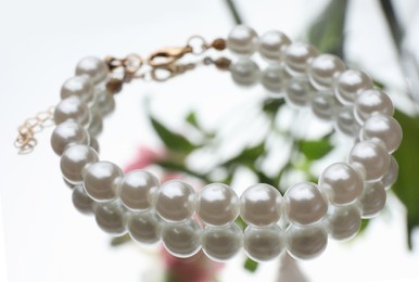 Photo of Elegant bracelet with pearls on mirror surface