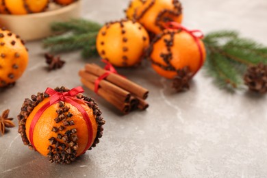 Photo of Pomander ball made of fresh tangerine and cloves on grey table, space for text