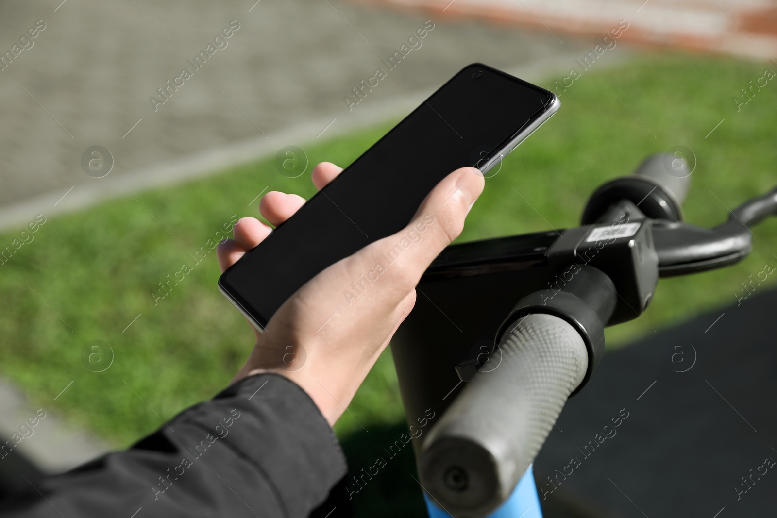 Photo of Man using smartphone to pay and unblock rental electric scooter outdoors, closeup