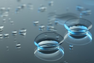 Photo of Pair of contact lenses on wet mirror surface, closeup. Space for text