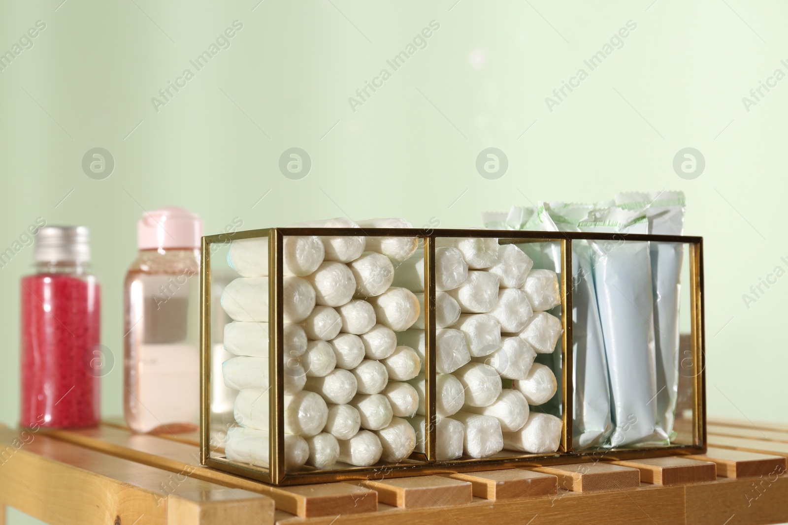 Photo of Organizer with many tampons on wooden table against light green background. Menstrual hygienic product