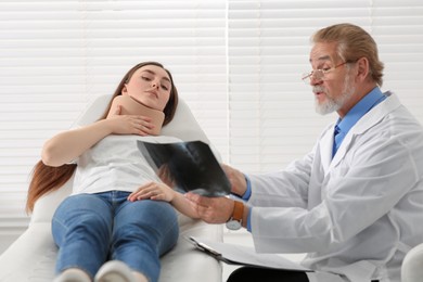 Orthopedist showing X-ray picture to patient in clinic