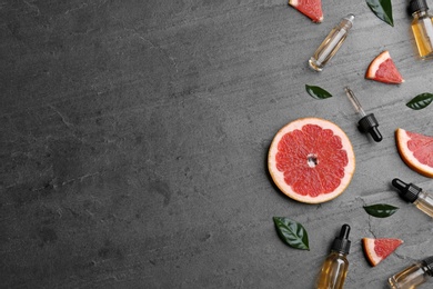 Photo of Flat lay composition with grapefruit slices and bottles of essential oil on grey background, space for text