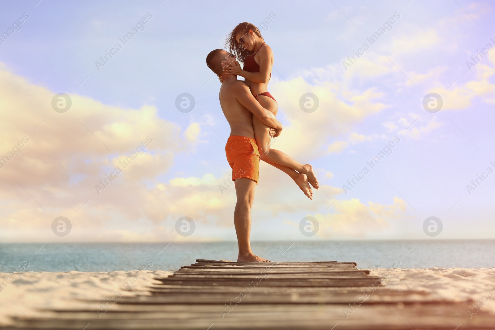 Photo of Young woman in bikini spending time with her boyfriend on beach. Lovely couple