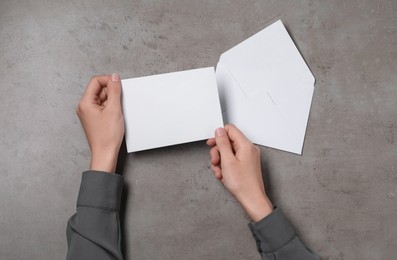 Photo of Woman with blank card at grey textured table, top view. Space for text
