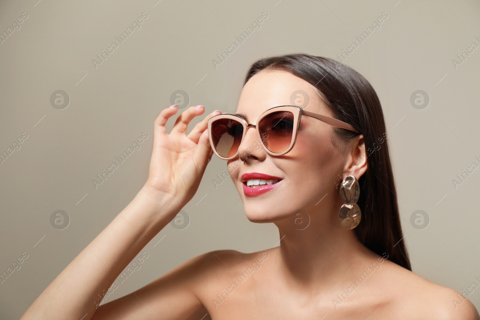 Photo of Beautiful woman in stylish sunglasses on beige background