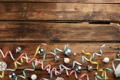 Flat lay composition with serpentine streamers and Christmas decor on wooden background. Space for text