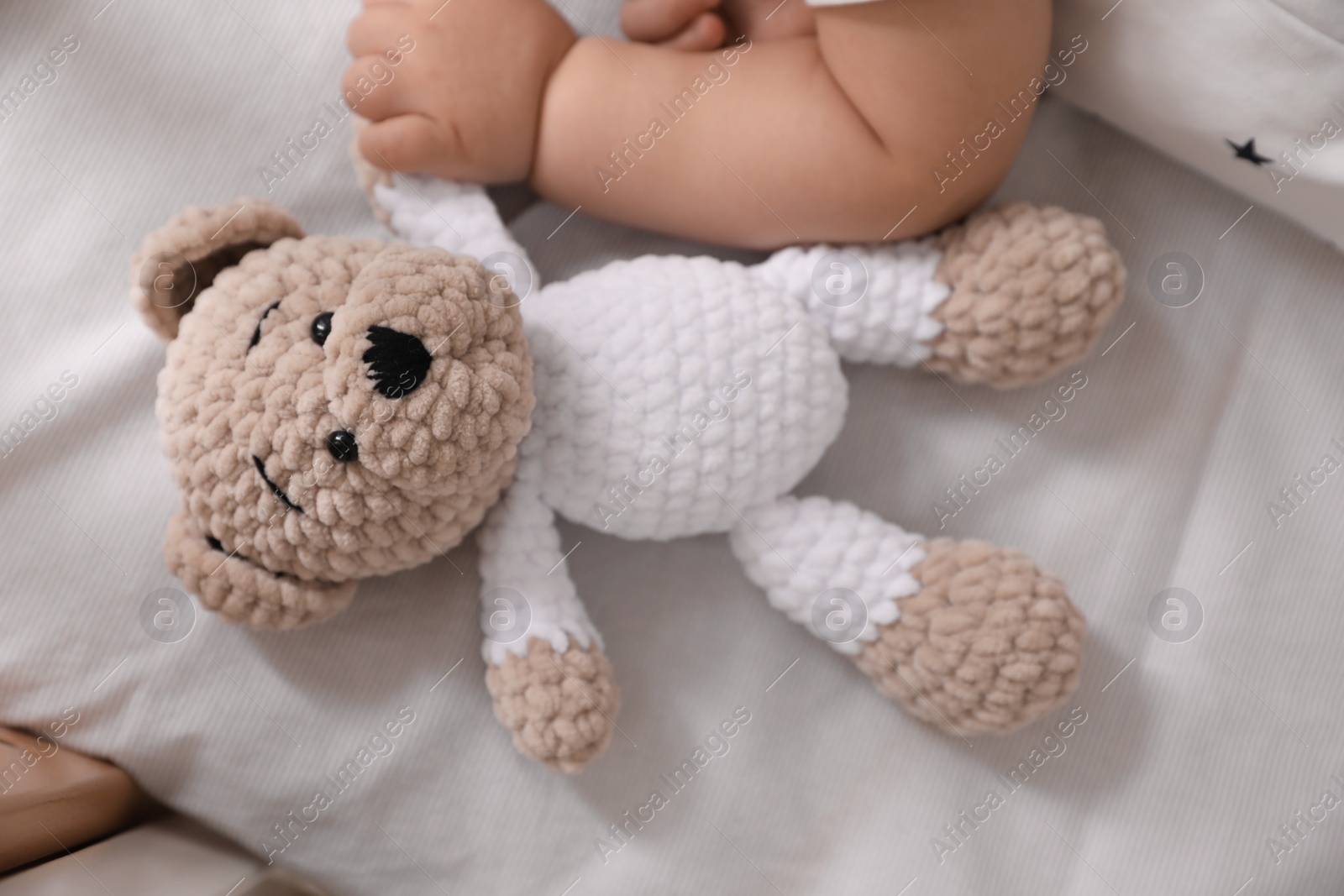 Photo of Adorable little baby with toy bear in bed, closeup