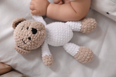 Photo of Adorable little baby with toy bear in bed, closeup