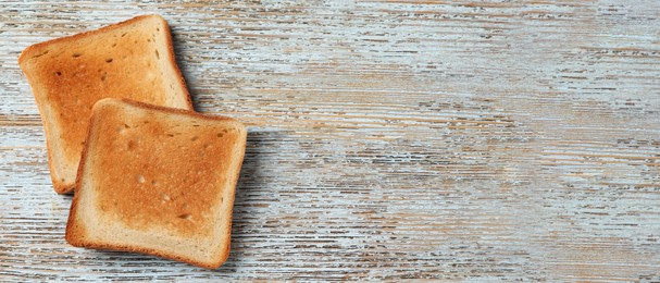 Slices of delicious toasted bread on wooden table, top view with space for text. Banner design