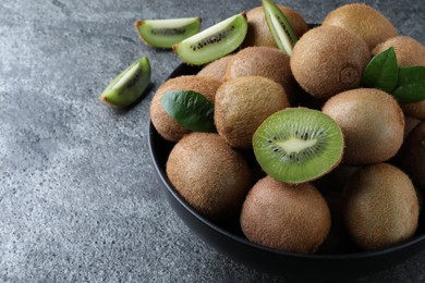 Fresh ripe kiwis in bowl on grey table, space for text