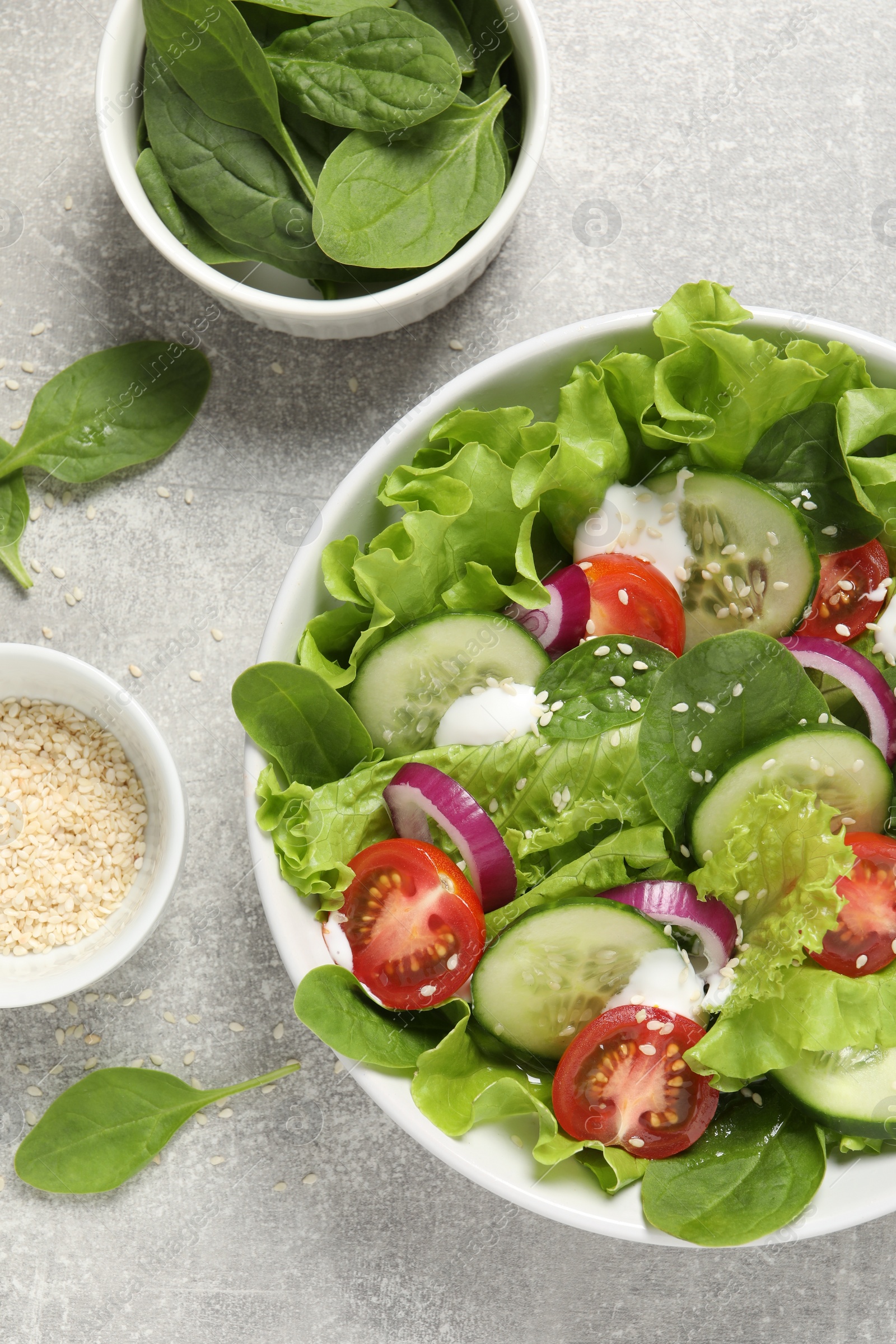 Photo of Delicious salad in bowl on light grey table, flat lay