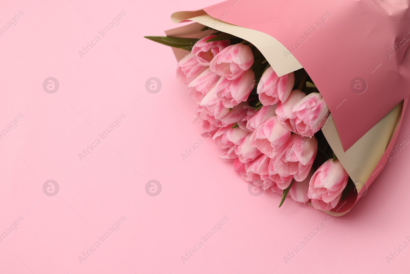 Photo of Beautiful bouquet of fresh tulips on pink background. Space for text