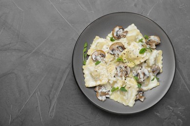 Photo of Delicious ravioli with tasty sauce and mushrooms on black table, top view. Space for text