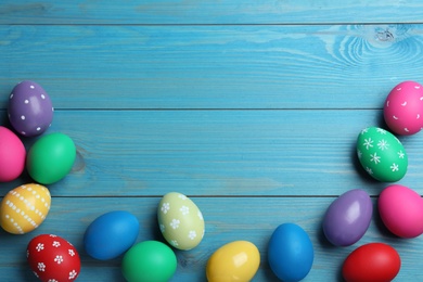 Photo of Colorful eggs on blue wooden background, flat lay with space for text. Happy Easter