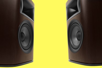 Photo of Wooden sound speakers on yellow background, closeup. Space for text