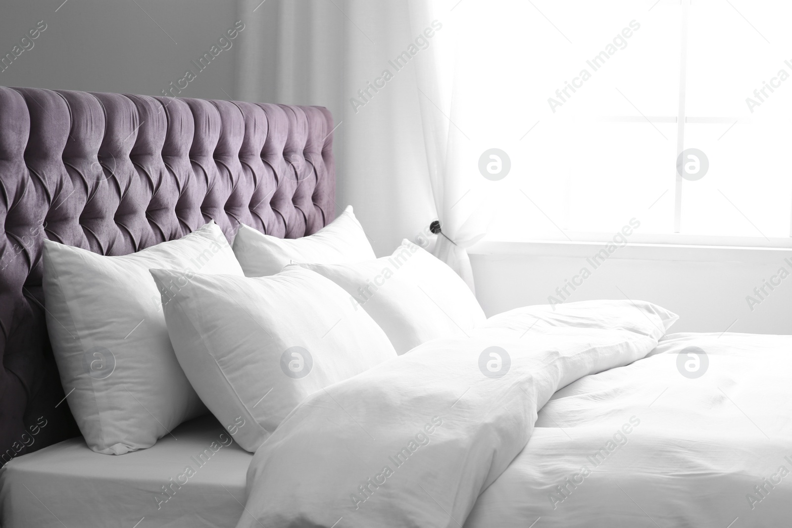 Photo of Modern bed with soft pillows near window