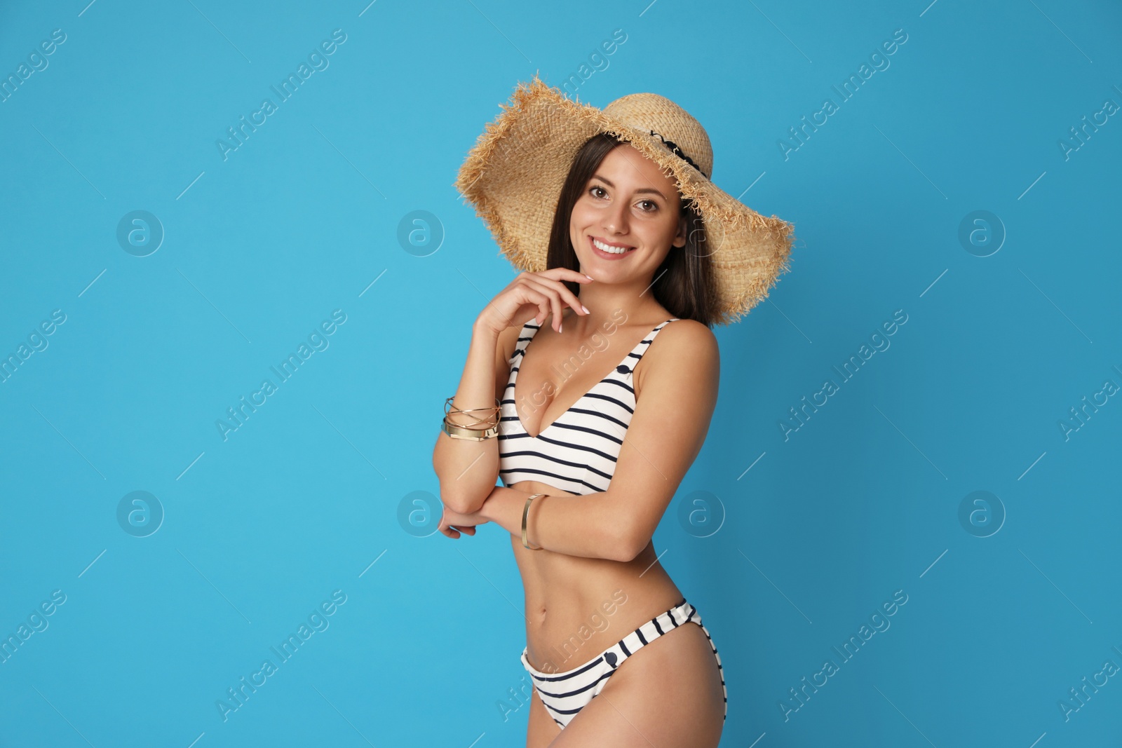 Photo of Pretty sexy woman with slim body in stylish striped bikini on blue background. Space for text