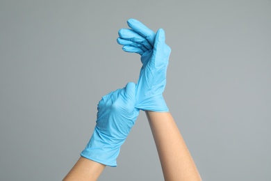 Photo of Doctor wearing medical gloves on grey background, closeup