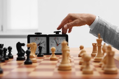 Photo of Man turning on chess clock during tournament at chessboard, closeup