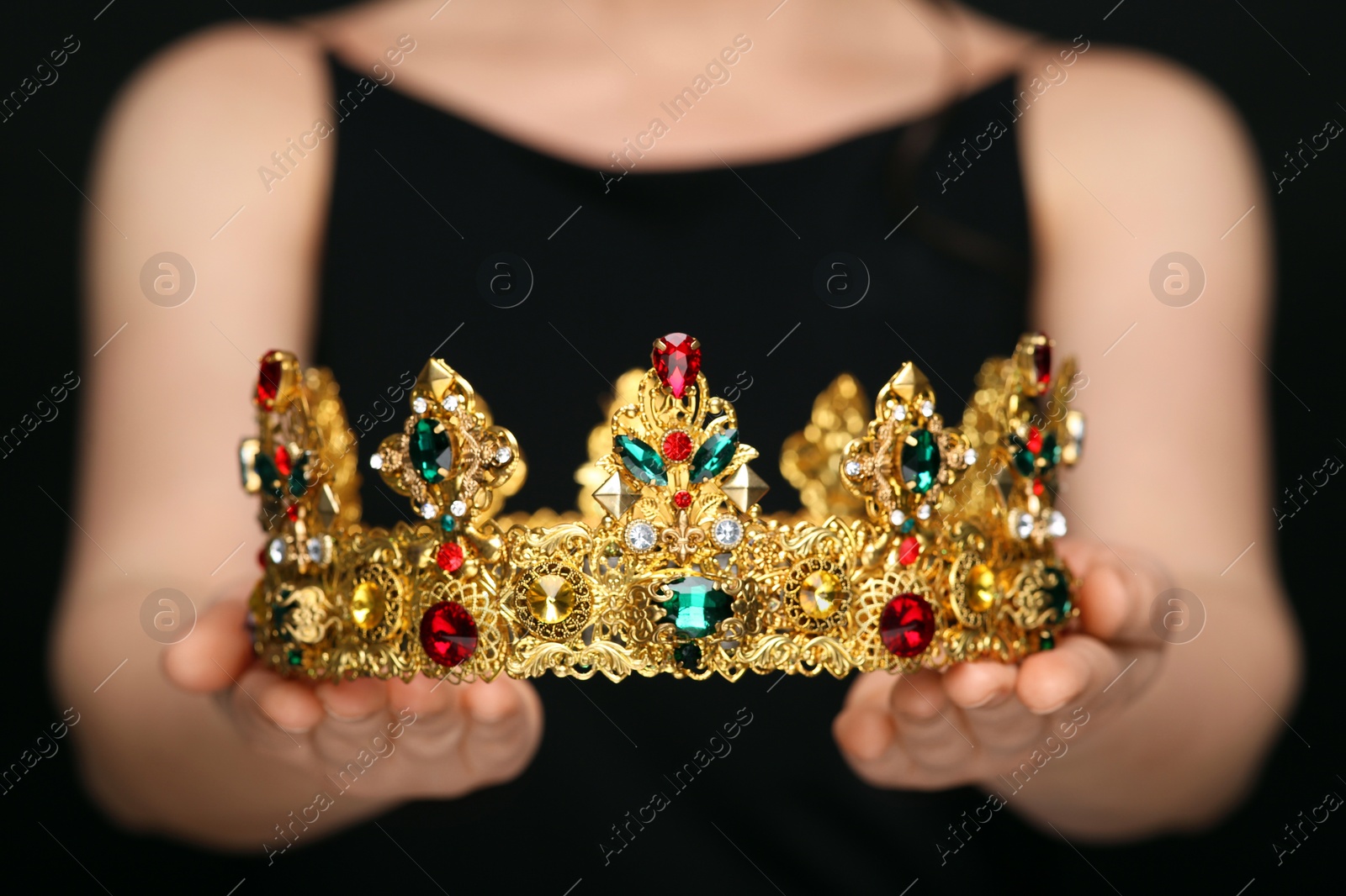 Photo of Woman holding luxurious crown on black background, closeup