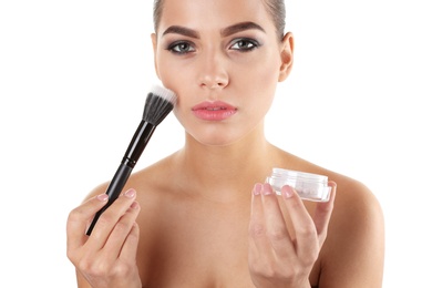 Portrait of beautiful woman applying face powder with makeup brush on white background