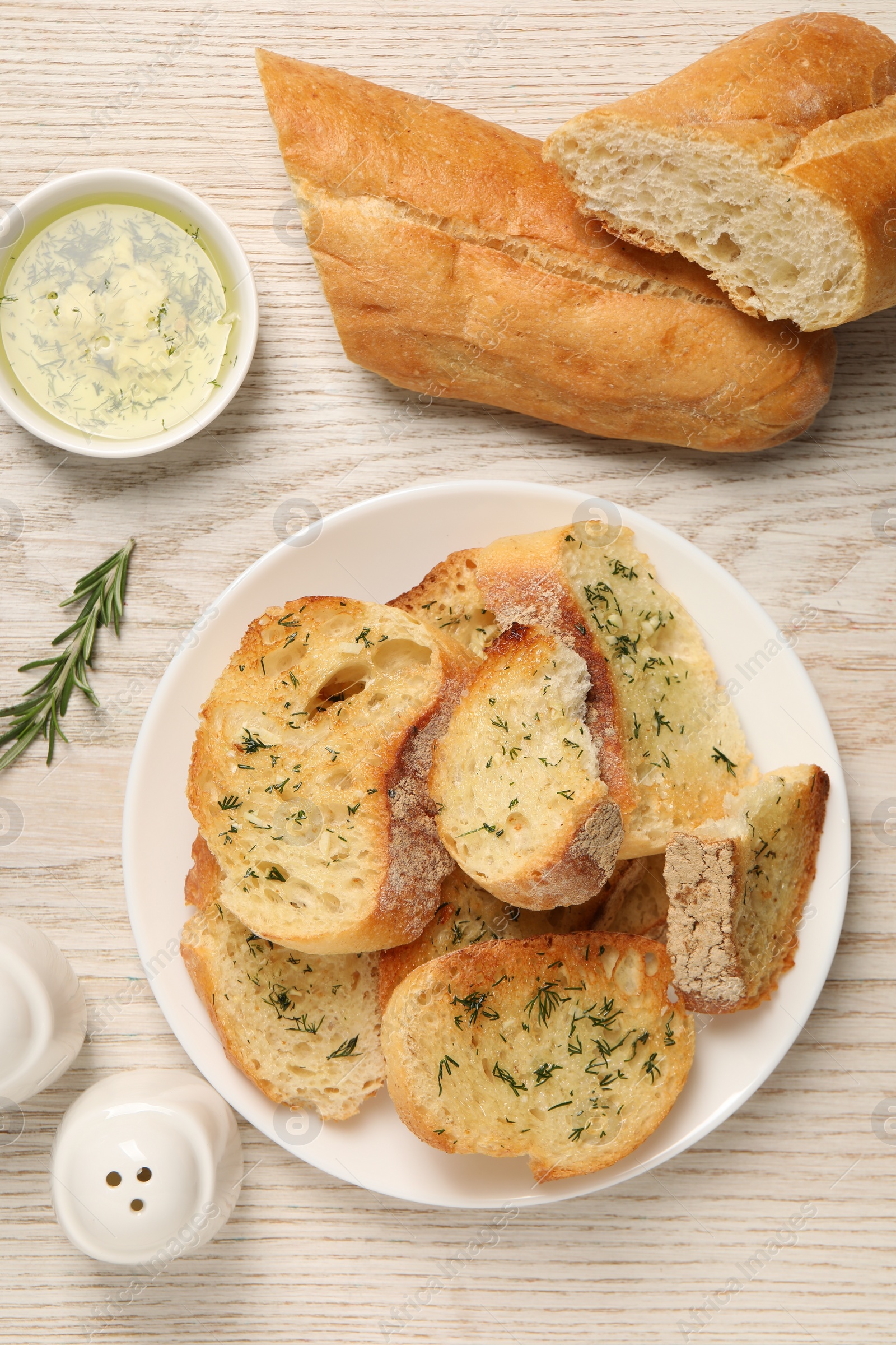 Photo of Tasty baguette with garlic served on white wooden table, flat lay