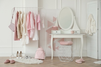 Photo of Dressing room interior with clothing rack and round mirror