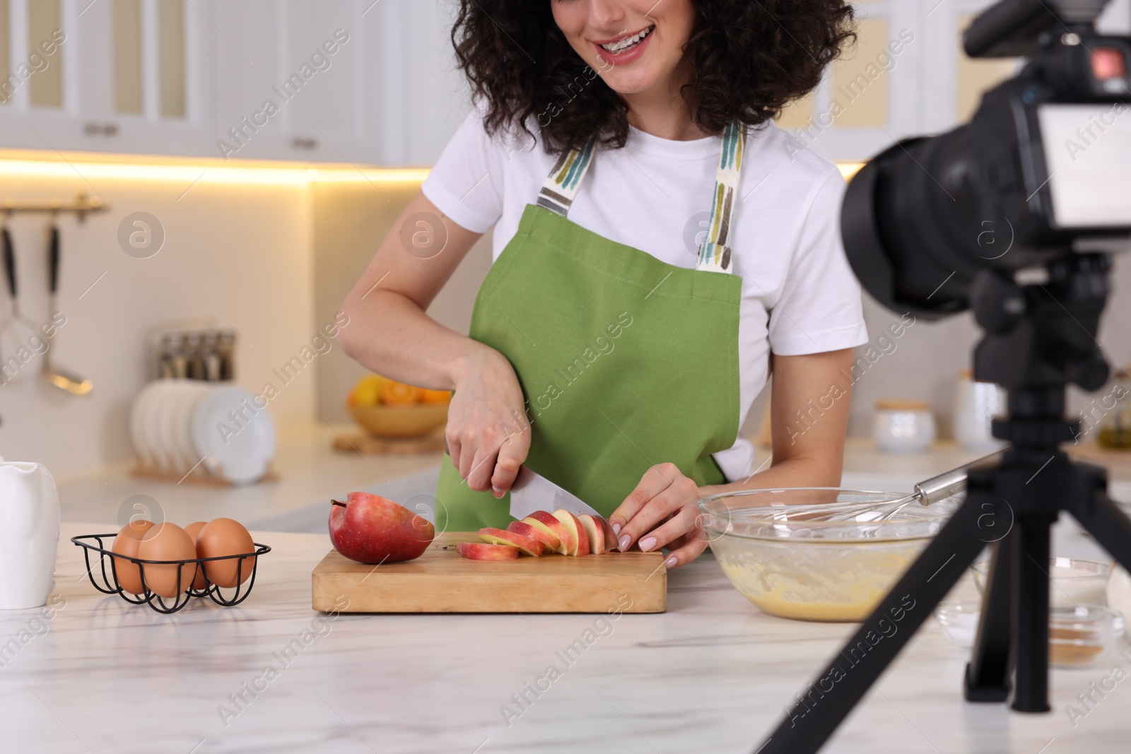 Photo of Smiling food blogger cooking while recording video in kitchen, closeup