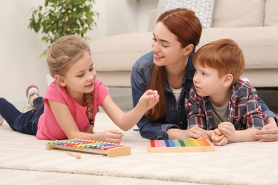 Photo of Happy mother and children playing with different math game kits on floor in room. Study mathematics with pleasure