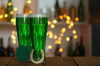 Green beer, horseshoe and clover on wooden counter, space for text. St.Patrick's Day celebration