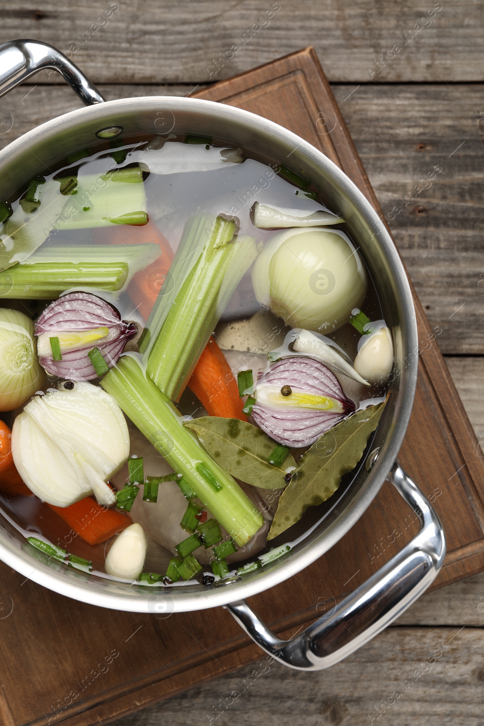 Photo of Different ingredients for cooking tasty bouillon in pot on wooden table, top view