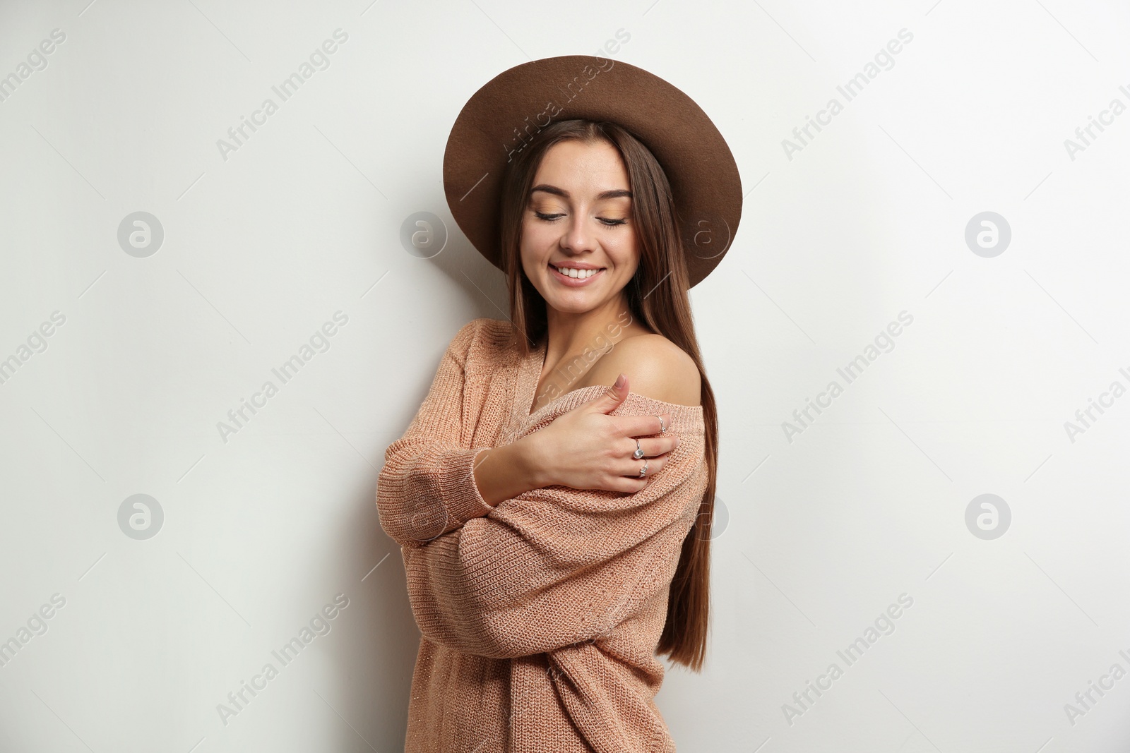 Photo of Beautiful young woman in warm sweater with hat on white background